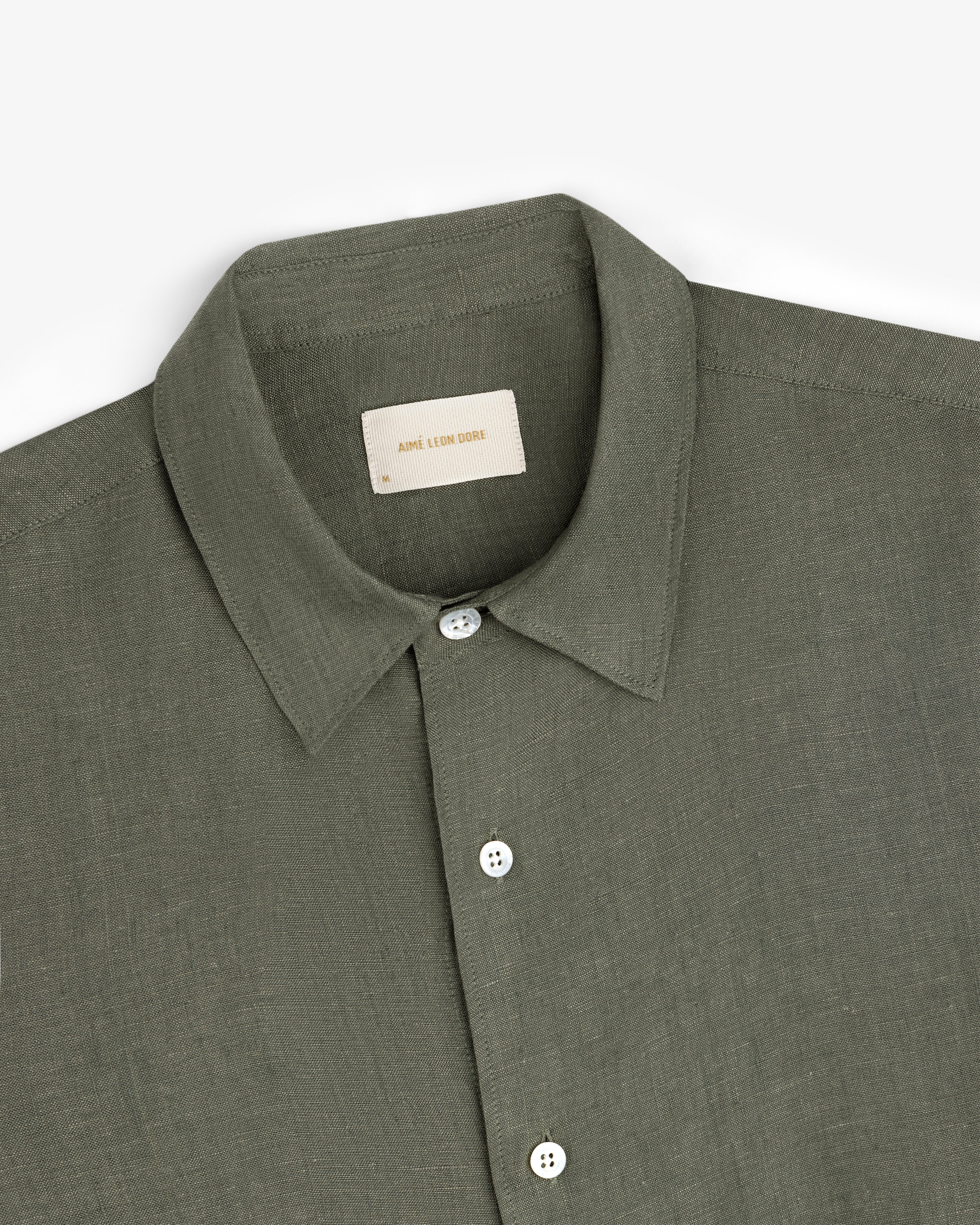 Long-Sleeve Linen Shirt in olive green with a collar and white buttons, folded neatly on a white background.