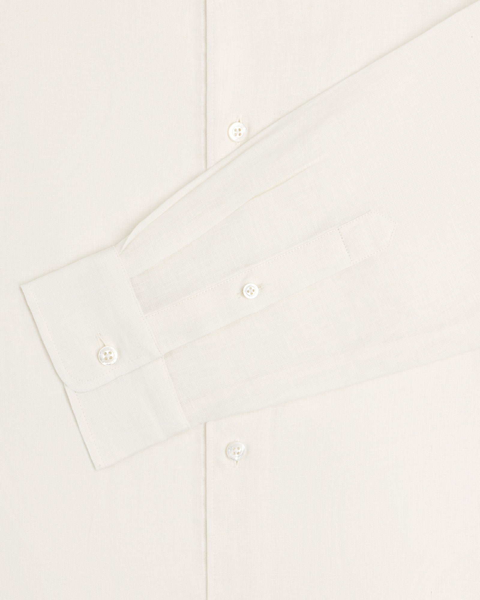 A close-up of the Long-Sleeve Linen Shirt in white, showing its buttons and cuff against a plain background.