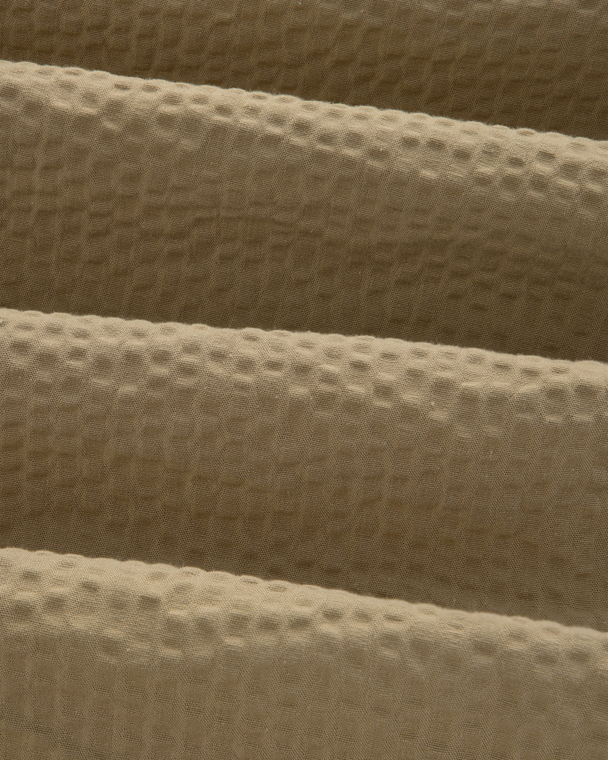 Close-up of the Short-Sleeve Seersucker Shirt's tan fabric, featuring a soft, textured waffle-like pattern.
