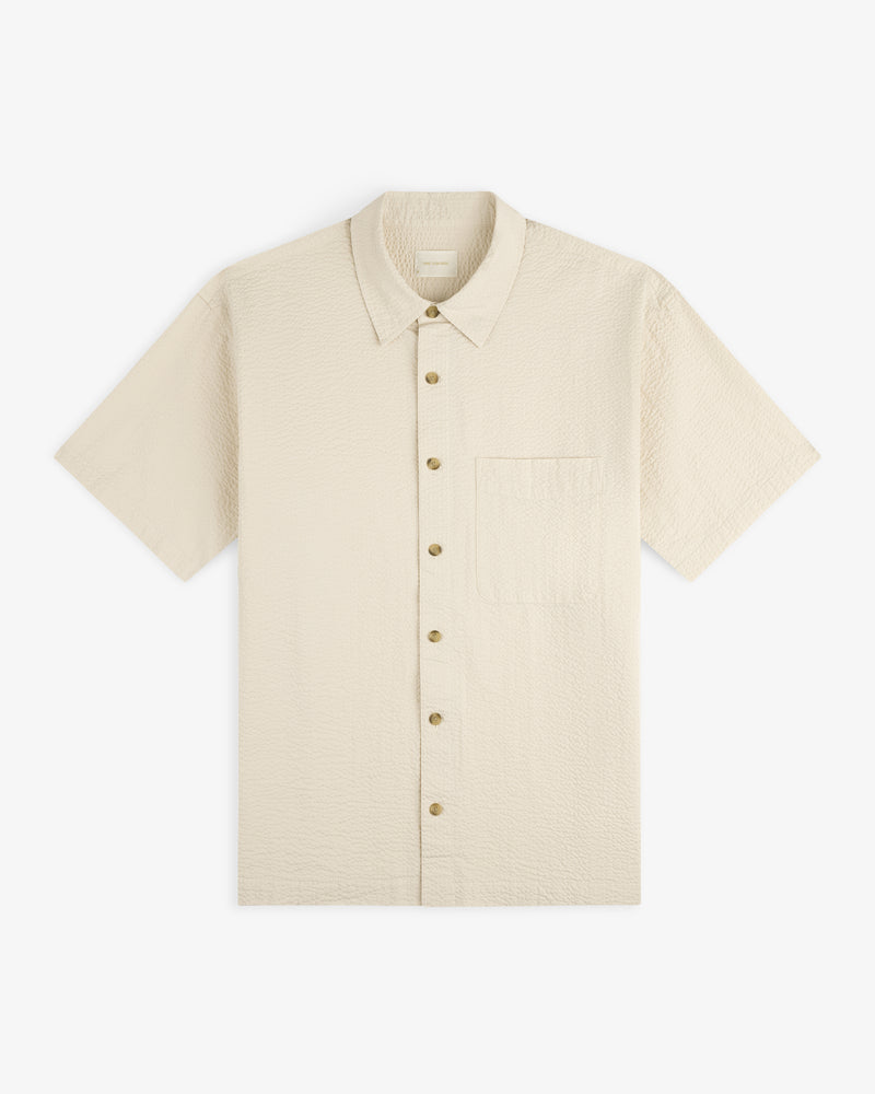 Short-Sleeve Seersucker Shirt in beige with a chest pocket, button-up, shown laid flat on a white background.