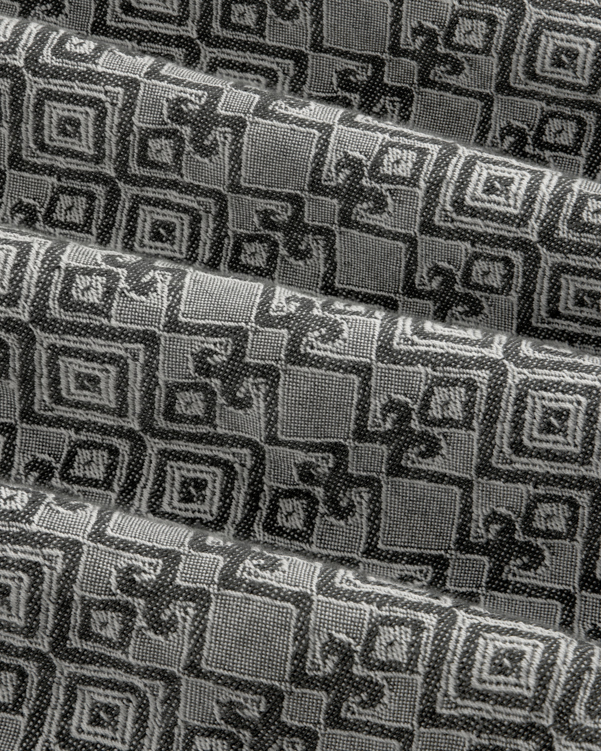 Jacquard Leisure Shirt in black and gray with geometric and floral patterns, shown in pleated diagonal folds.
