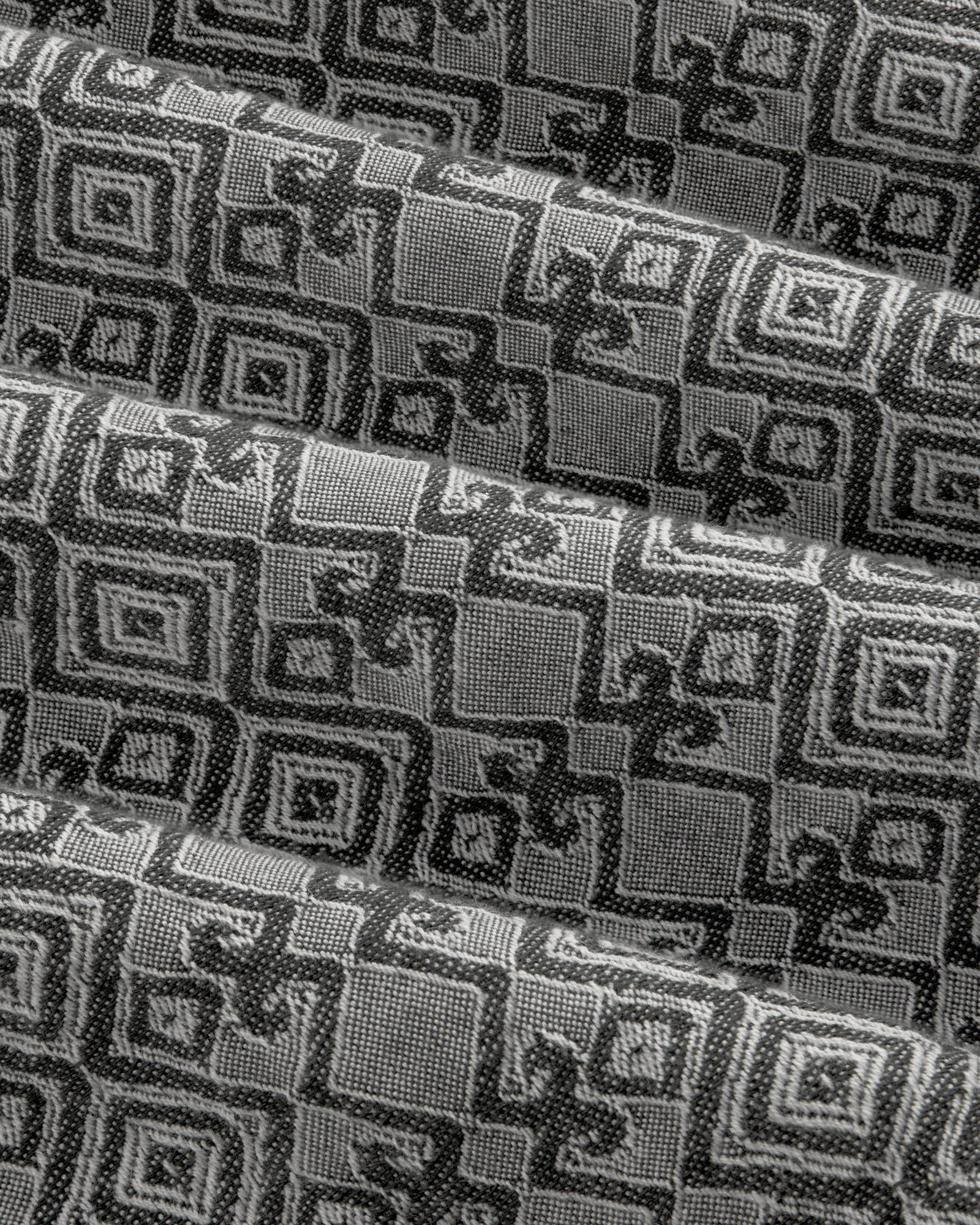 Jacquard Leisure Shirt in black and gray with geometric and floral patterns, shown in pleated diagonal folds.