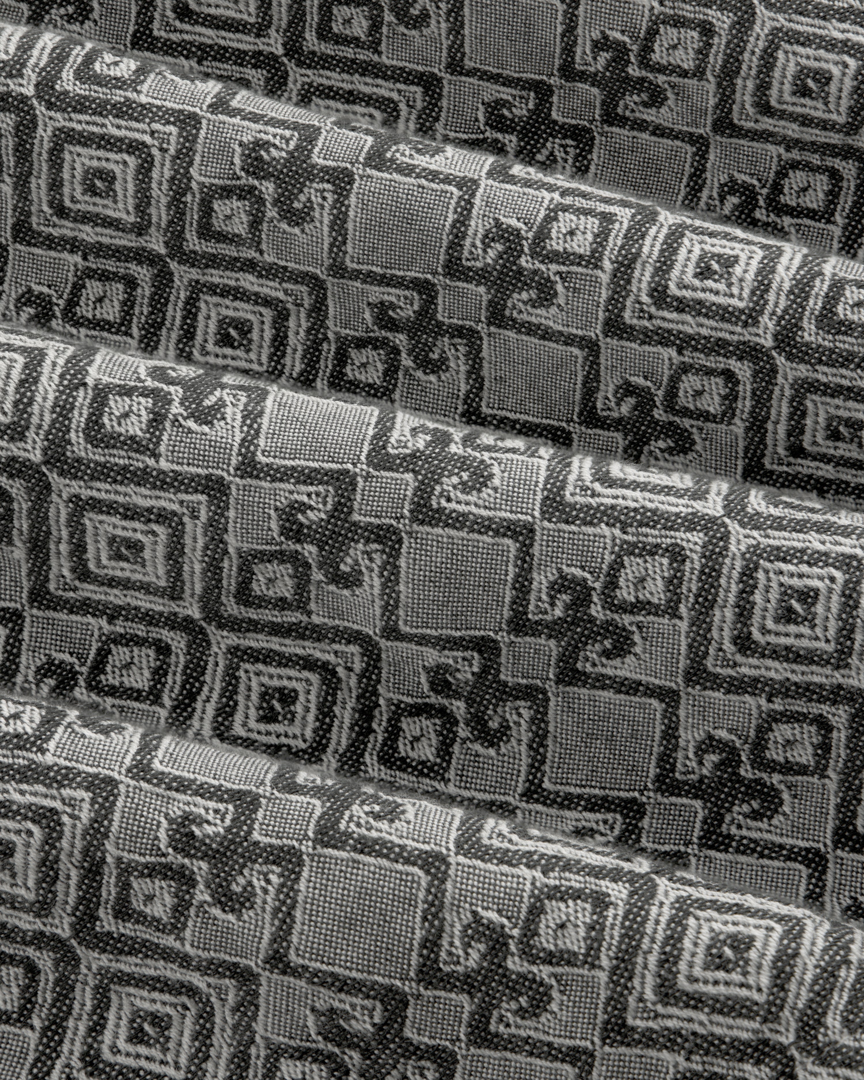 Jacquard Leisure Shirt in black and gray with geometric and floral patterns, shown in pleated diagonal folds.