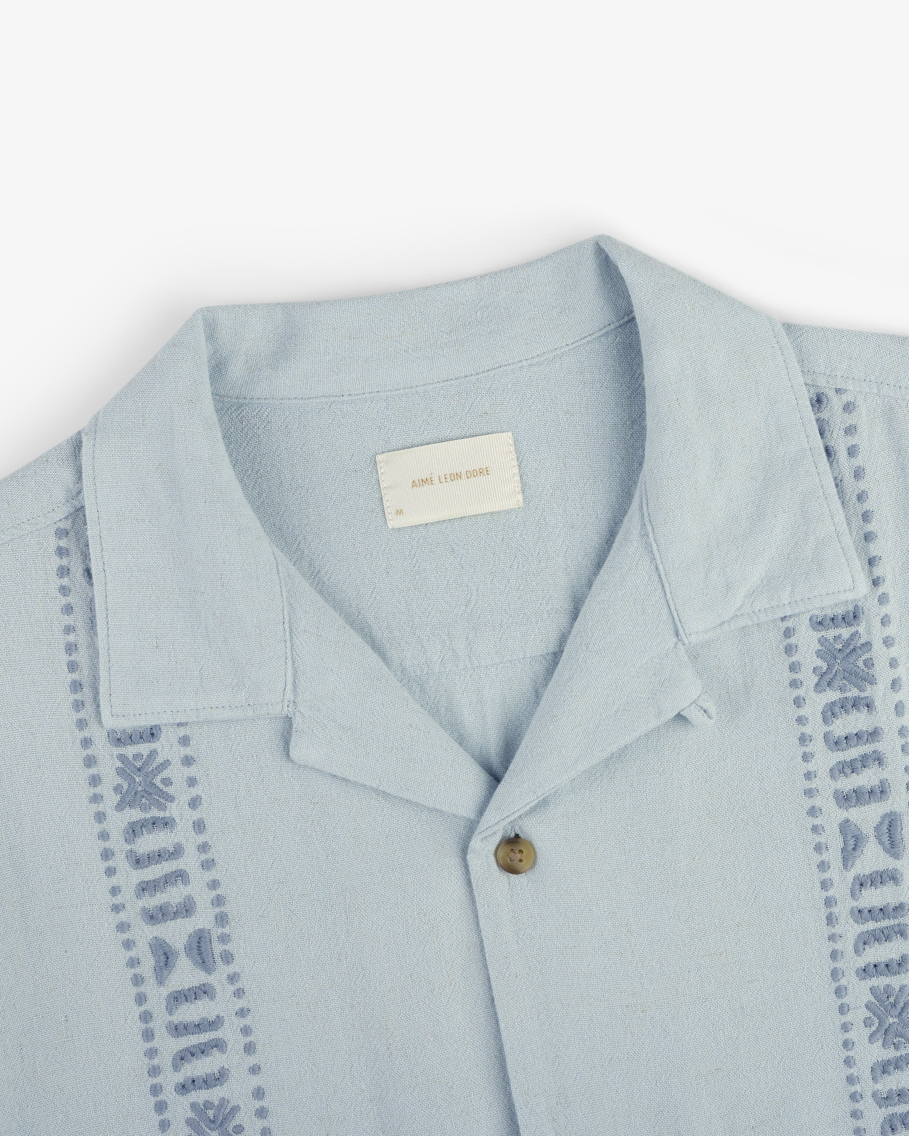 Linen Blend Leisure Shirt in light blue with decorative stitching and a single brown button, laid flat on white.