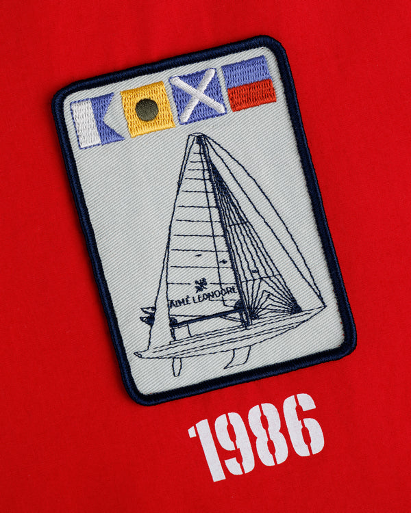 The Marina Jacket features an embroidered sailing patch with nautical flags and “1986” on a red background.