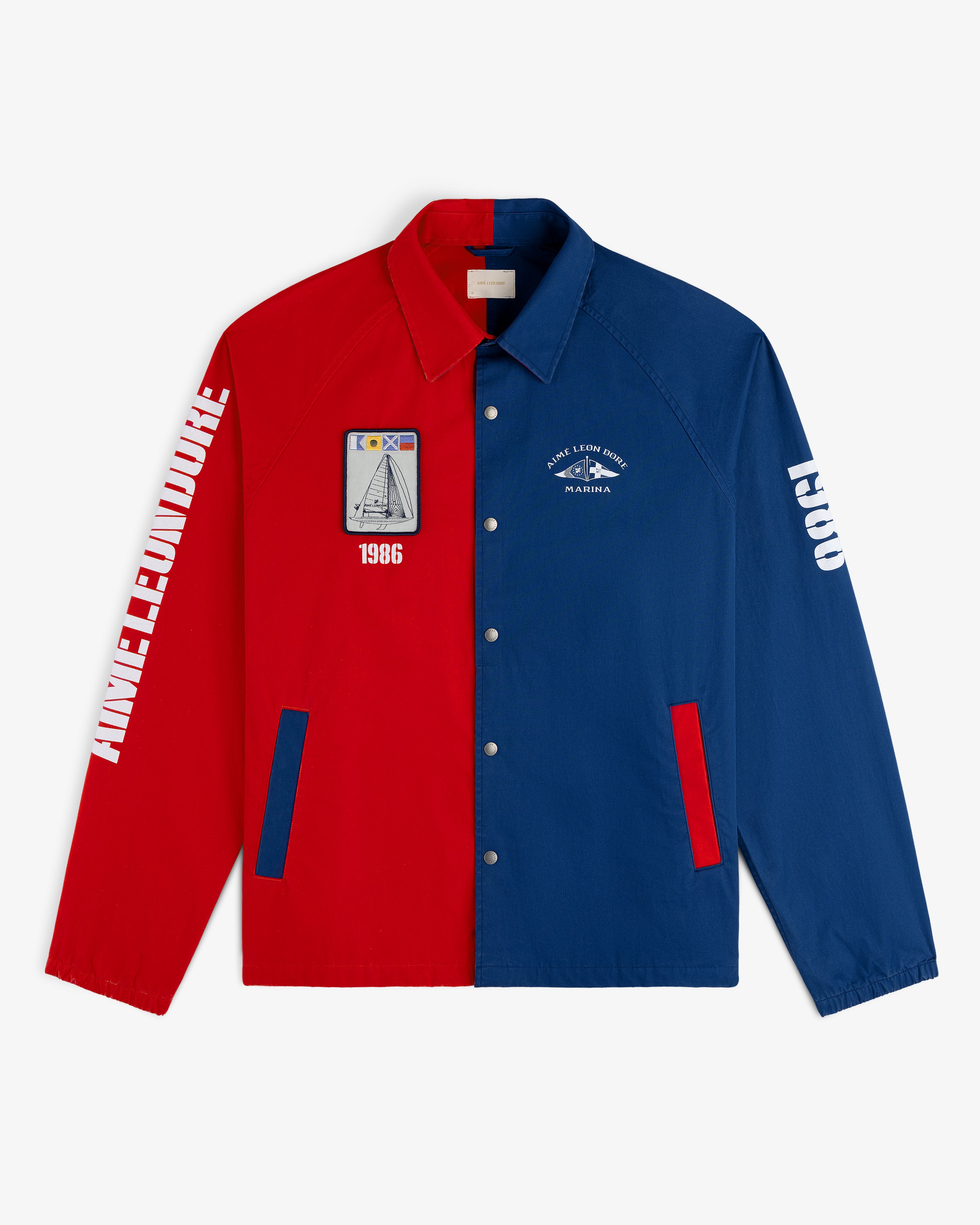Marina Jacket, half red and half blue, features graphic patches and white text on both sleeves, laid flat.