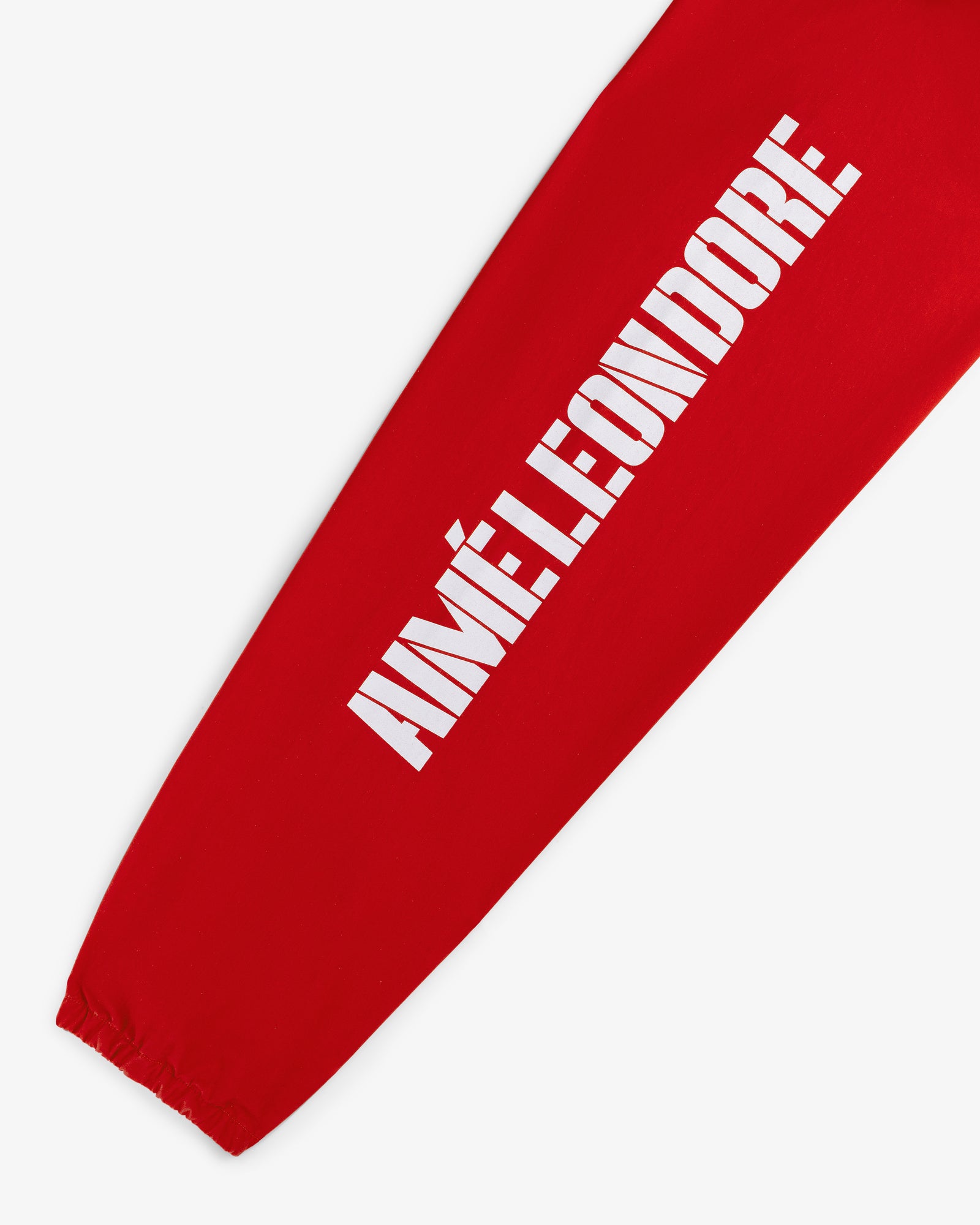 Red sleeve of the Marina Jacket with bold white AIMÉ LEON DORE text printed vertically and an elastic wrist cuff.