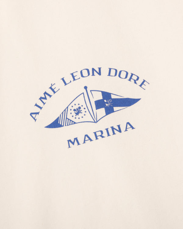 The Marina Jacket features blue Aimé Leon Dore Marina text and two nautical flags on a cream background.
