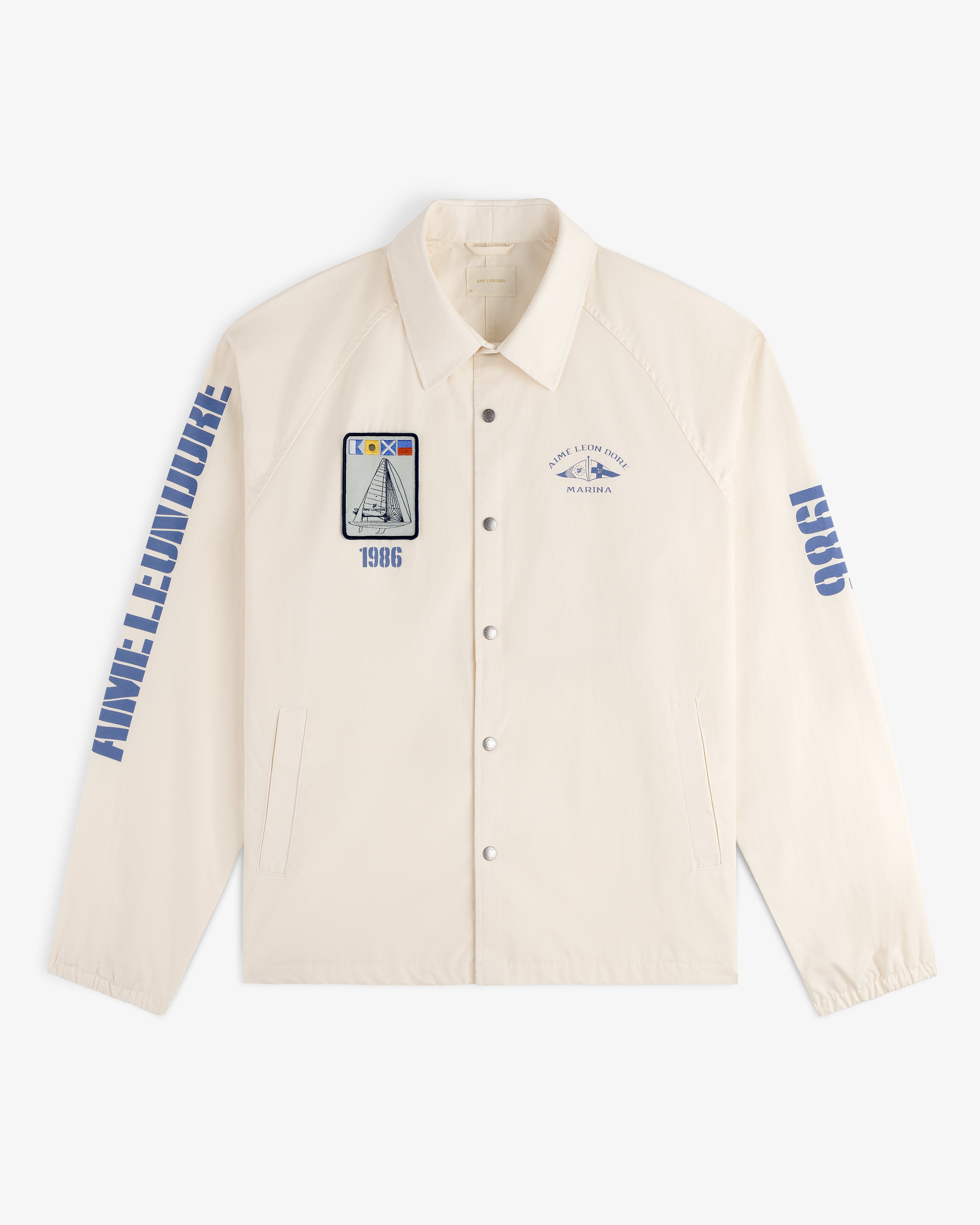 Marina Jacket: Cream button-up with blue graphics, patches, text, and a sailboat illustration on the front.