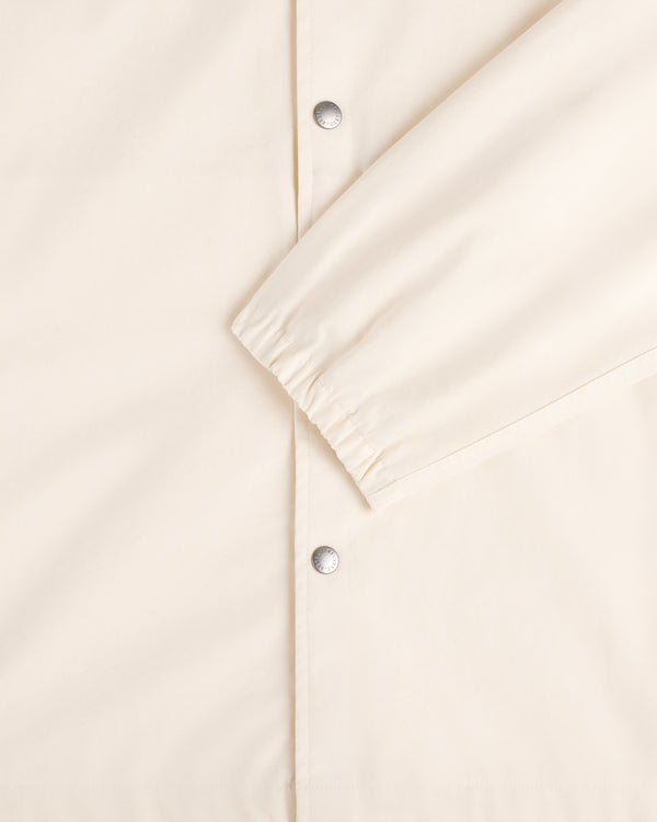 Close-up of the Marina Jacket in cream with silver snap buttons and an elastic cuff on one sleeve.