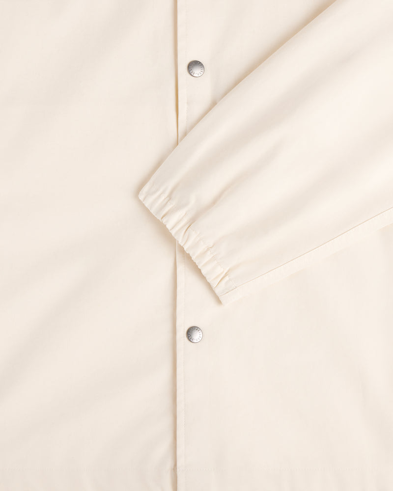 Close-up of the Marina Jacket in cream with silver snap buttons and an elastic cuff on one sleeve.