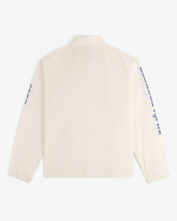 Back view of the Marina Jacket, a cream-colored design featuring blue square patterns along both sleeves.