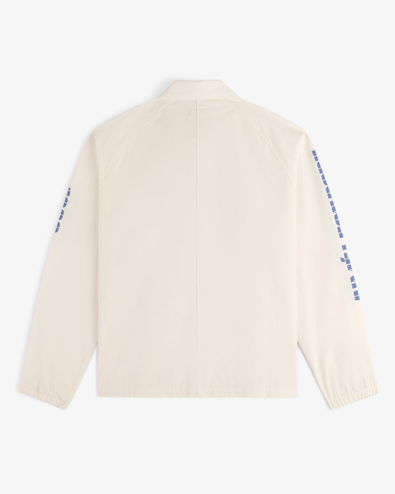 Back view of the Marina Jacket, a cream-colored design featuring blue square patterns along both sleeves.