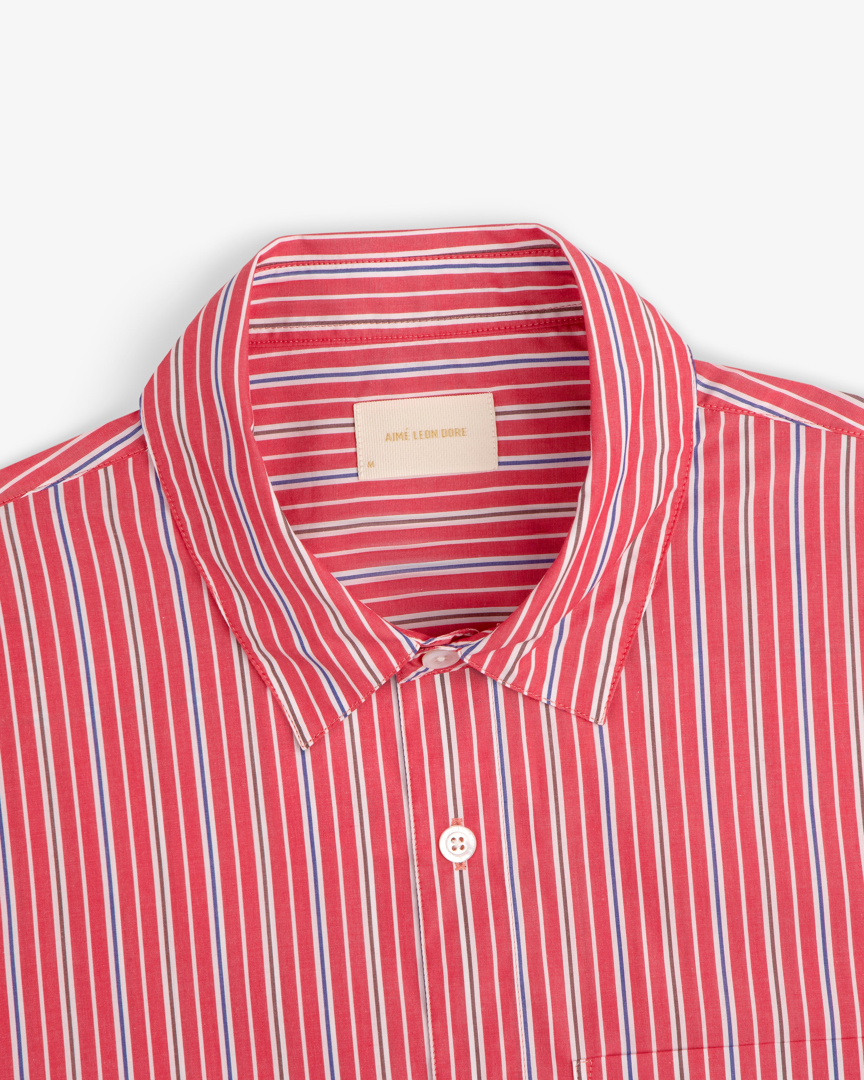 Aimé Leon Dore Yarn Dyed Striped Shirt with red, blue, and white stripes, spread collar, and branded label.