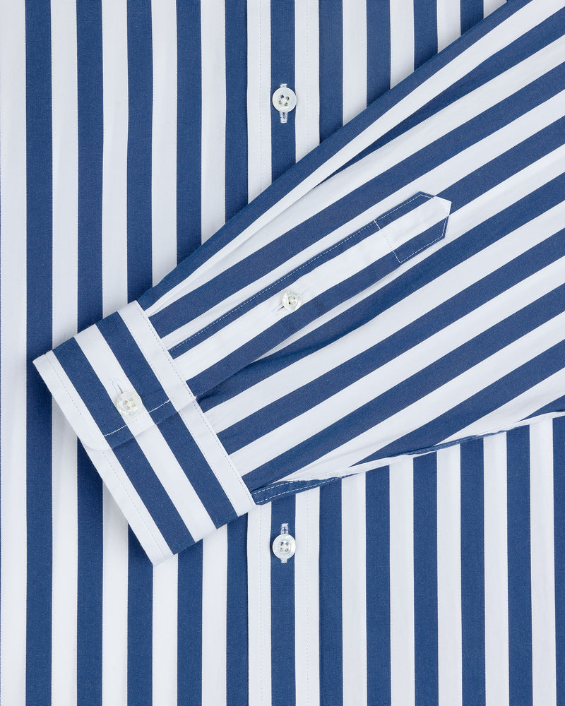 The Striped Leon Overshirt is a blue and white vertically striped long-sleeve shirt with buttoned cuffs.