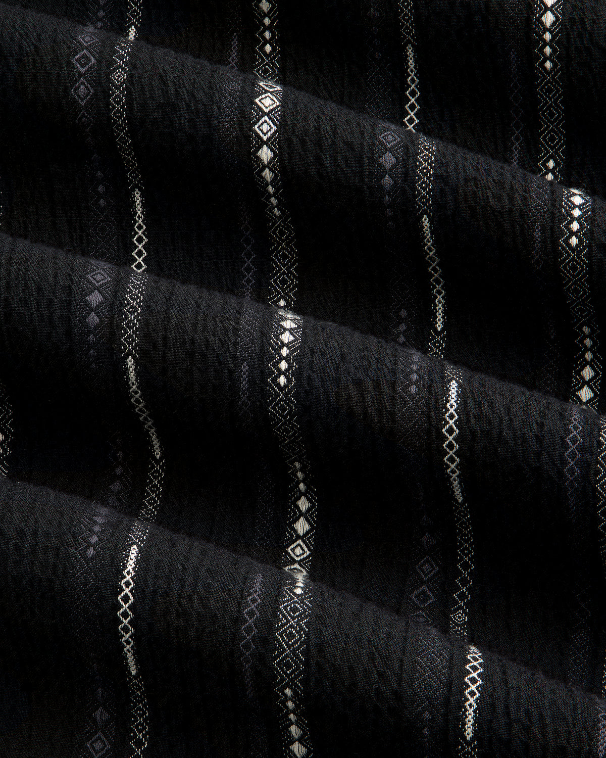 Black Cropped Jacquard Camp Shirt featuring textured fabric with horizontal white geometric patterns and ridges.