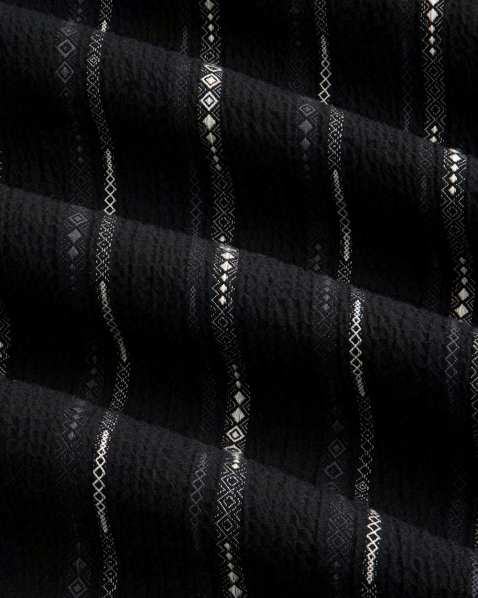 Black Cropped Jacquard Camp Shirt featuring textured fabric with horizontal white geometric patterns and ridges.