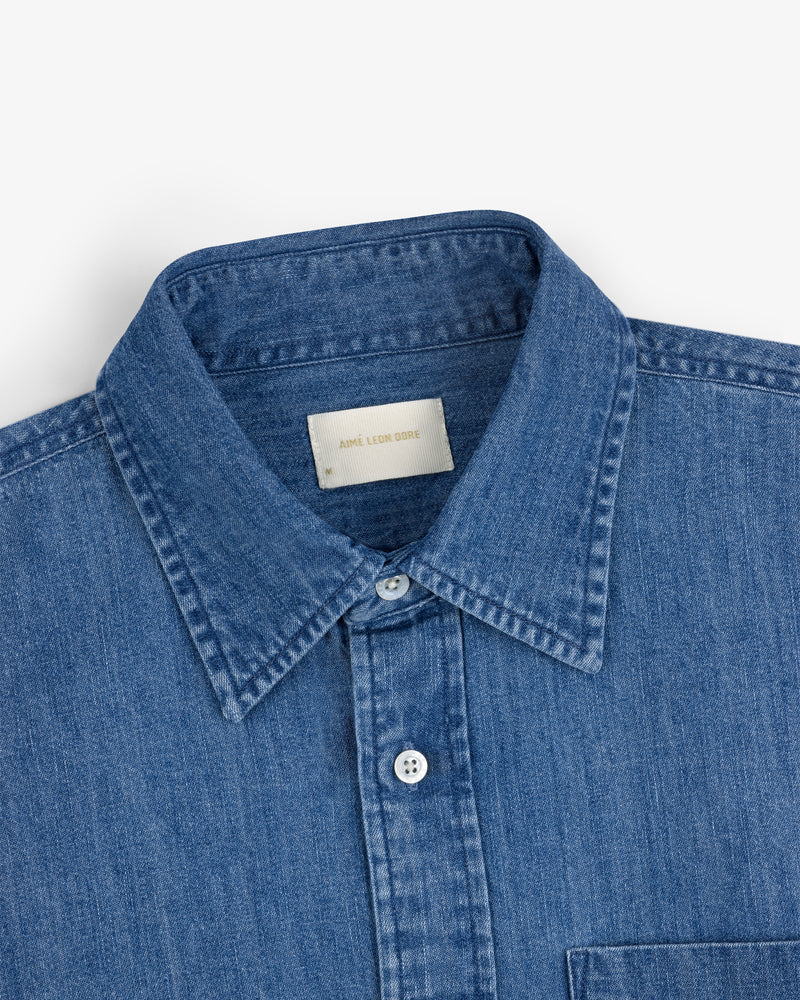 Crest Chambray Shirt: blue denim button-up with a collar and a visible white label inside the neck.