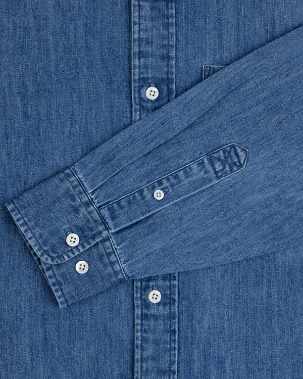 Crest Chambray Shirt with white buttons and long sleeves folded across the front.