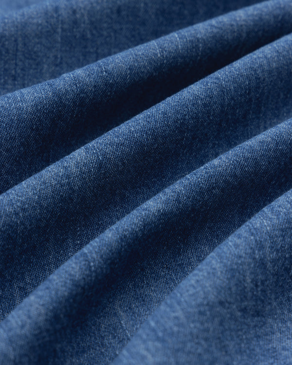 Close-up of Crest Chambray Shirt’s blue denim fabric, showing soft folds and diagonal textured lines.