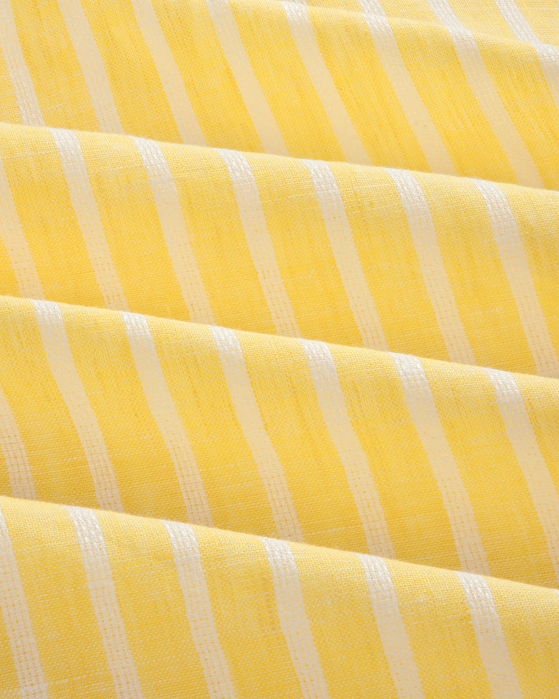 Yellow striped linen casual shirt with white vertical stripes and soft, even folds across the fabric.