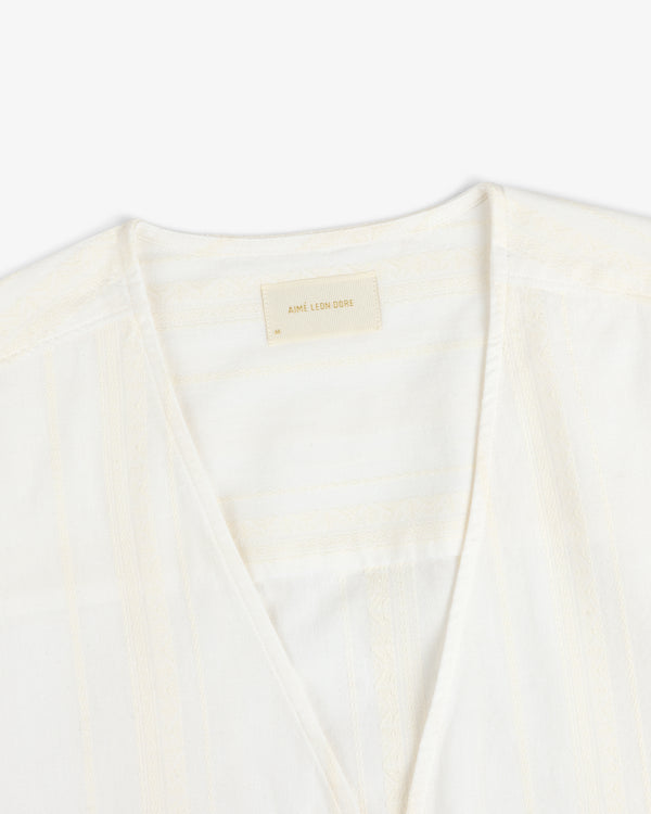 Close-up of a white Jacquard Striped Tie-Front Shirt with a beige Aime Leon Dore label on the inner neckline.