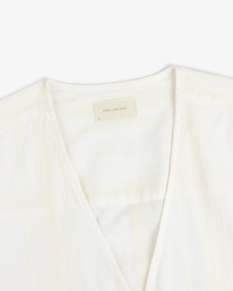 Close-up of a white Jacquard Striped Tie-Front Shirt with a beige Aime Leon Dore label on the inner neckline.