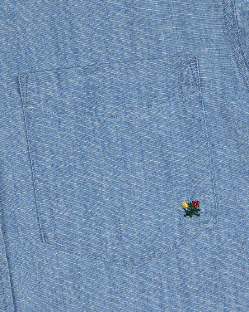 Crest Chambray Shirt with a light blue pocket and tiny yellow and red flowers embroidered at the lower right corner.