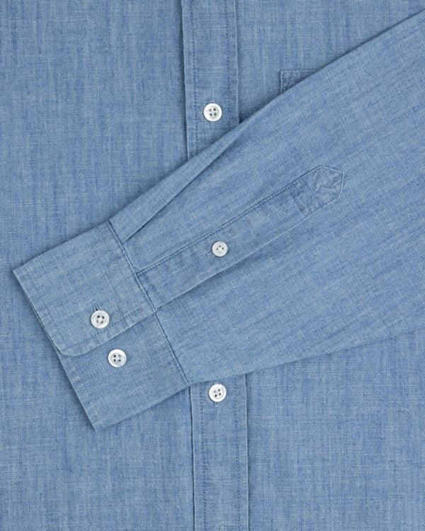 Crest Chambray Shirt in light blue, long sleeve with white buttons, shown flat with one sleeve folded across front.