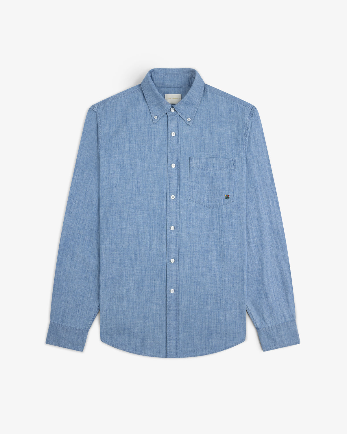 Crest Chambray Shirt in light blue with long sleeves and chest pocket, laid flat on a white background.