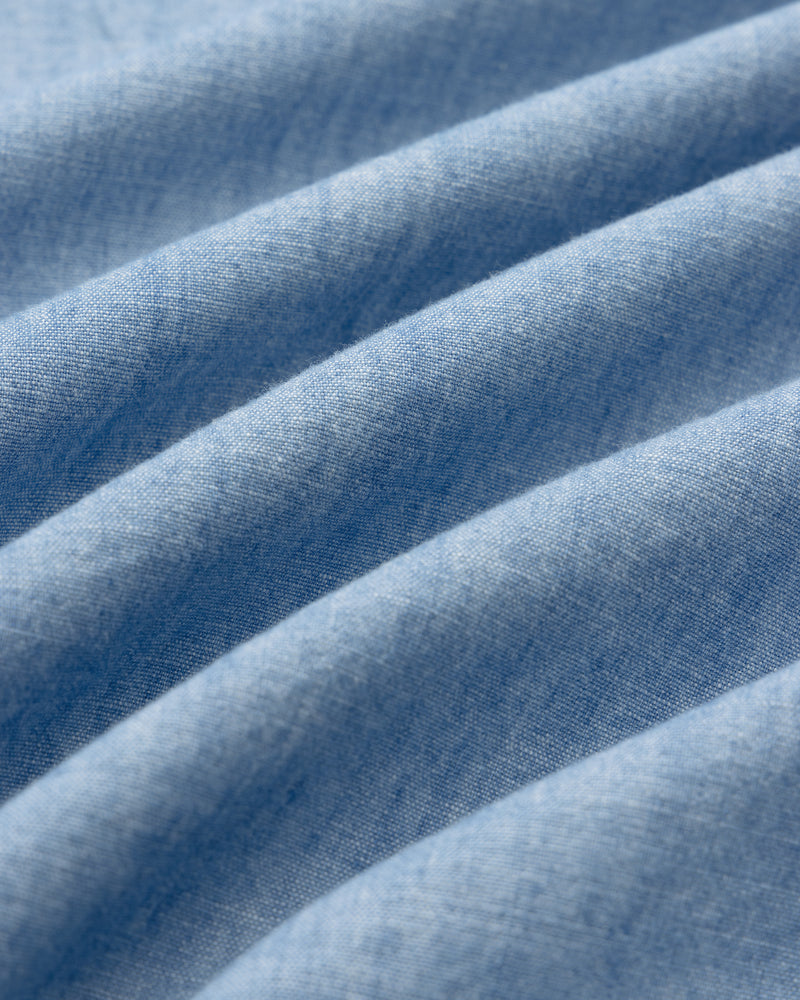 Close-up of Crest Chambray Shirt in light blue, showing soft folds and textured, wavy pattern.