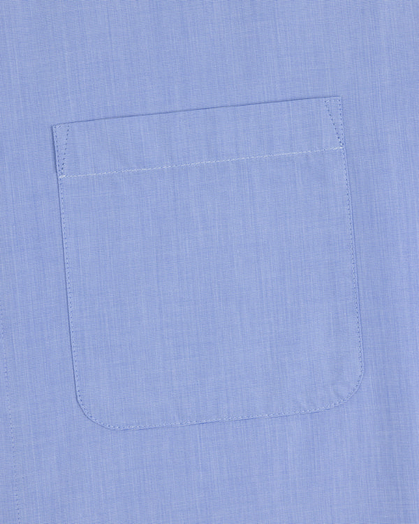 A close-up of the Poplin Casual Shirt pocket in light blue, showing visible stitching on smooth fabric.