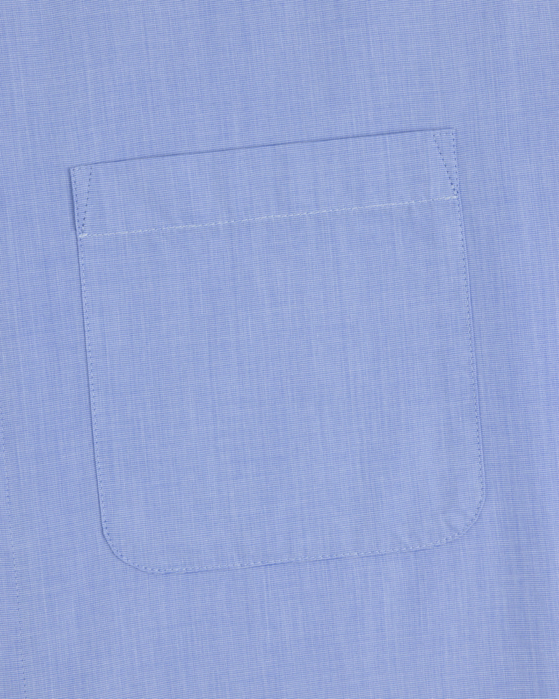 A close-up of the Poplin Casual Shirt pocket in light blue, showing visible stitching on smooth fabric.
