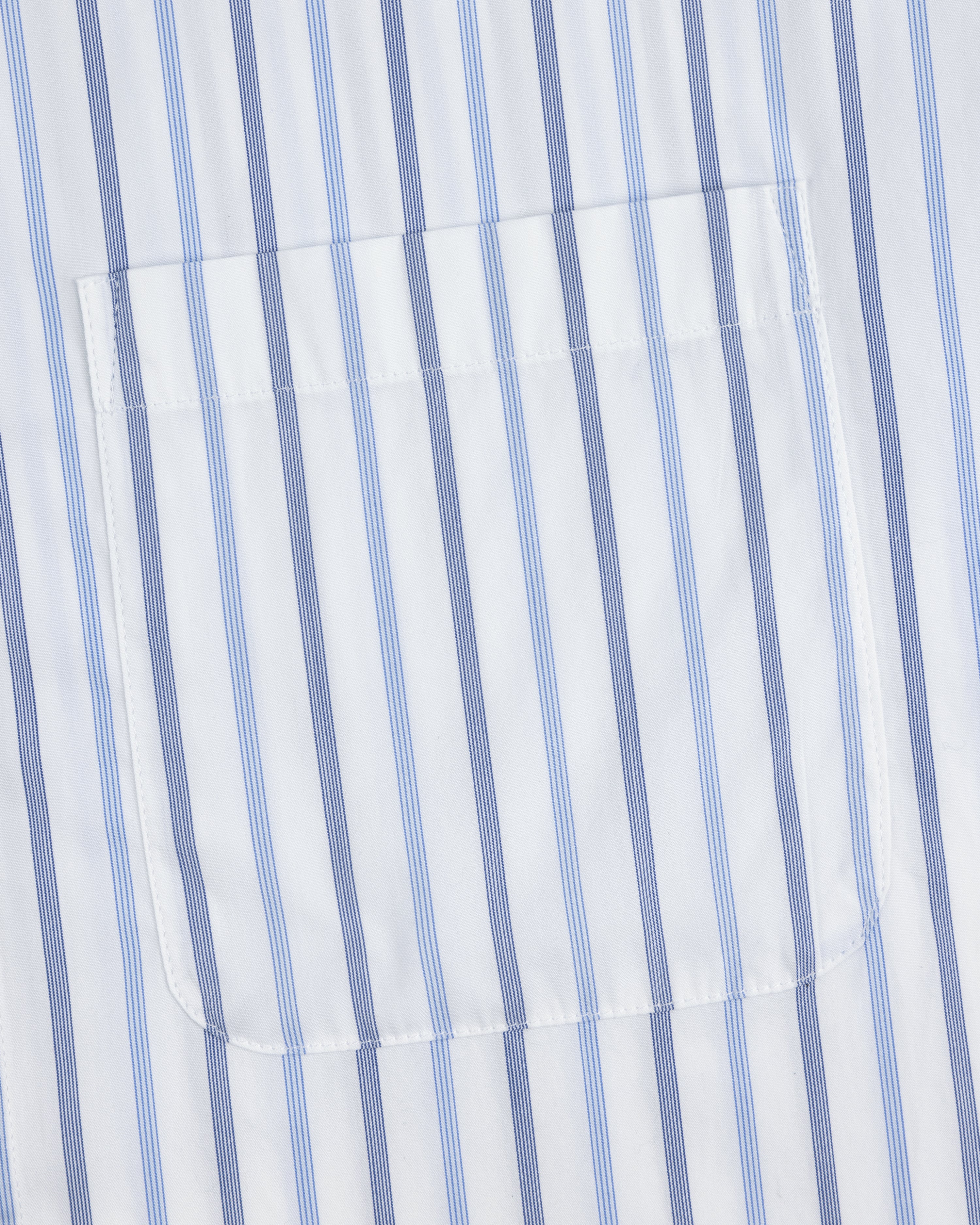 Close-up of Poplin Casual Shirt pocket on white fabric with vertical blue and light blue stripes.