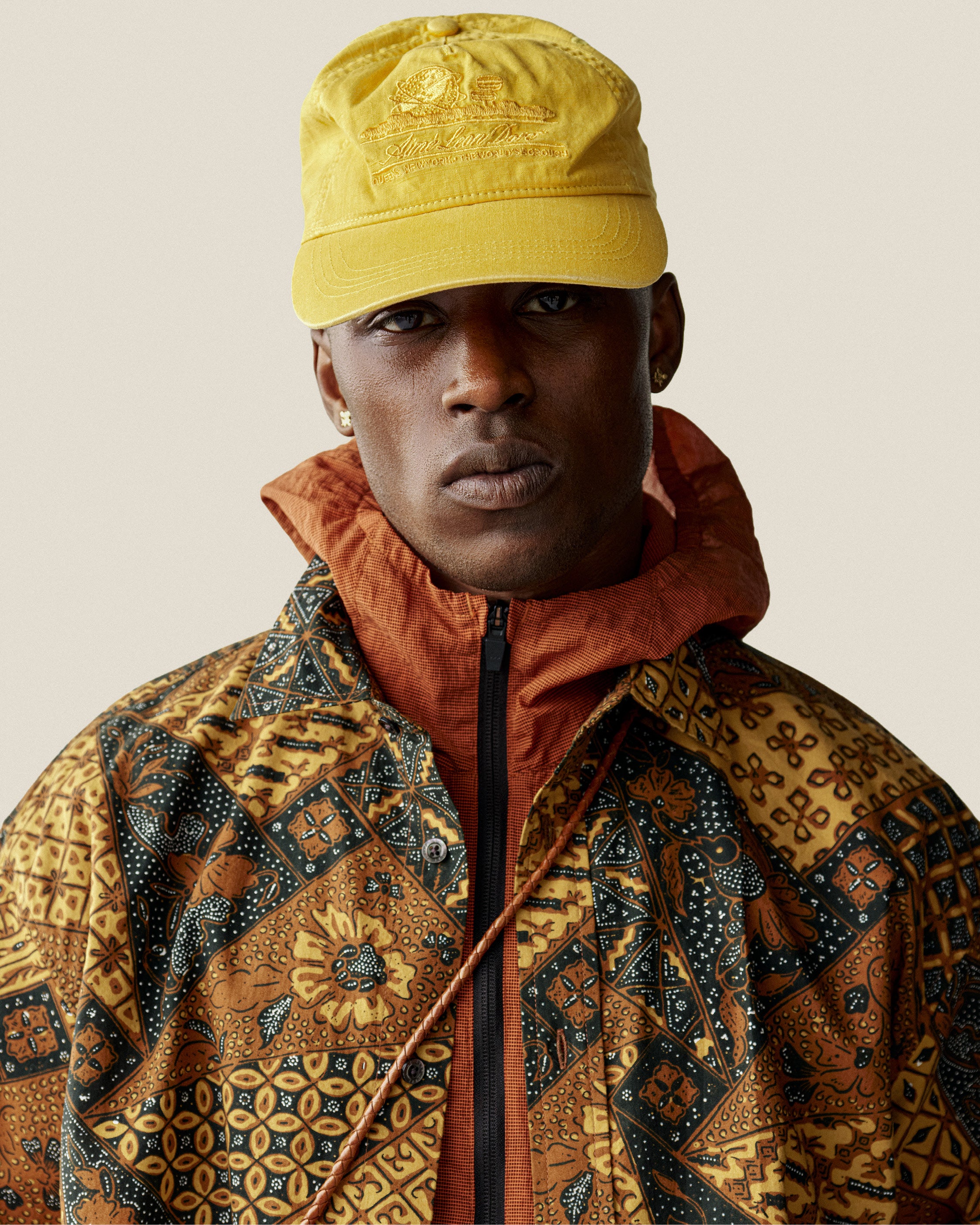 Man wearing the Sun Faded Unisphere Hat and a patterned jacket with orange collar, looking at the camera.