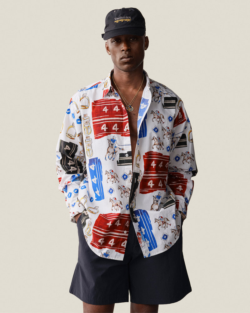 Man in a Printed Leon Overshirt, dark shorts, and black cap stands against a plain light background.