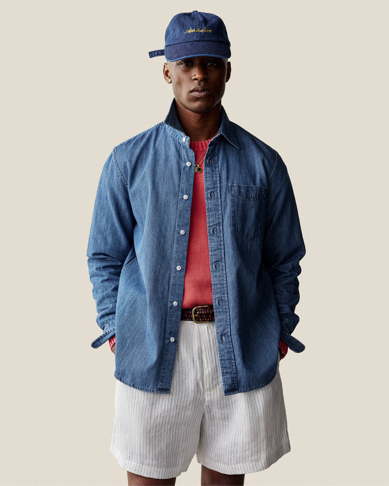 A man wears the Washed Inside Out Sweater over a red shirt, white striped shorts, and a blue cap against a plain background.
