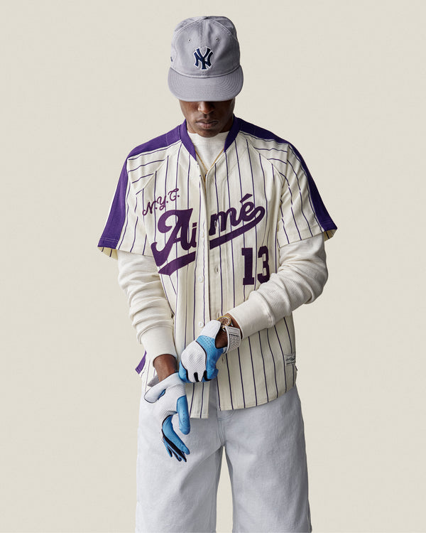 Man wearing a Long-Sleeve Waffle Thermal and white pants looks down while putting on a blue glove and cap.