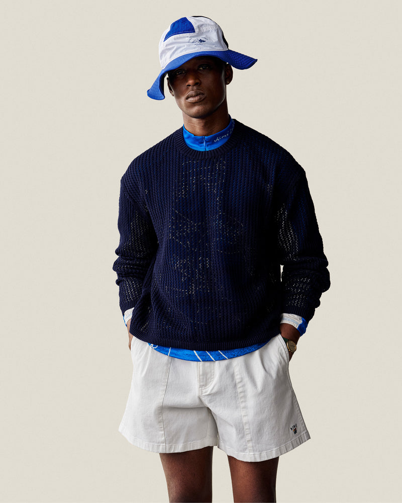 A person wears the Fassianos Half-Zip Cycling Jersey with white shorts and a blue-and-white bucket hat against a light background.
