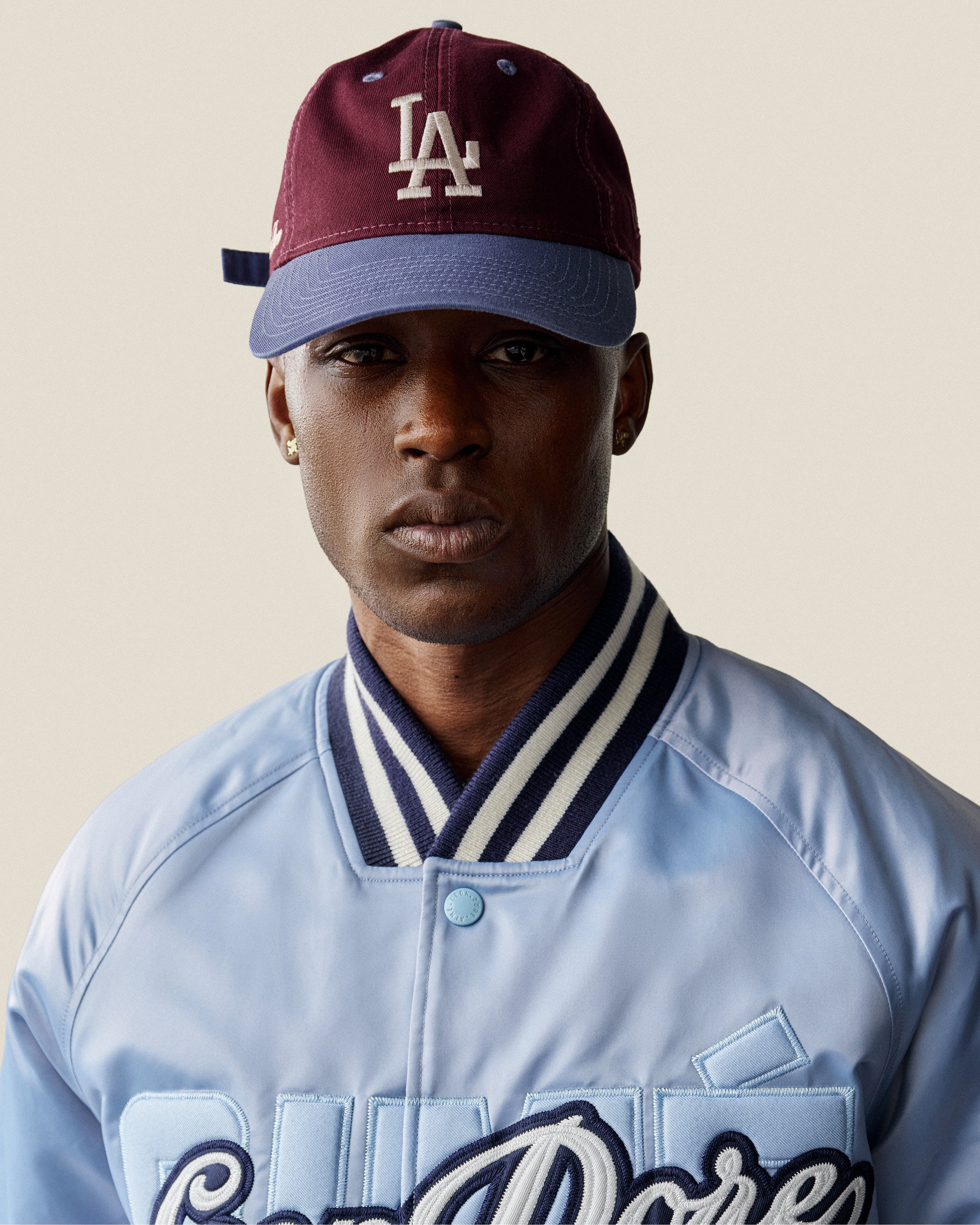 A person wearing the ALD / LA Dodgers Colorblock Ballpark Hat and a light blue jacket with dark stripes, facing the camera.