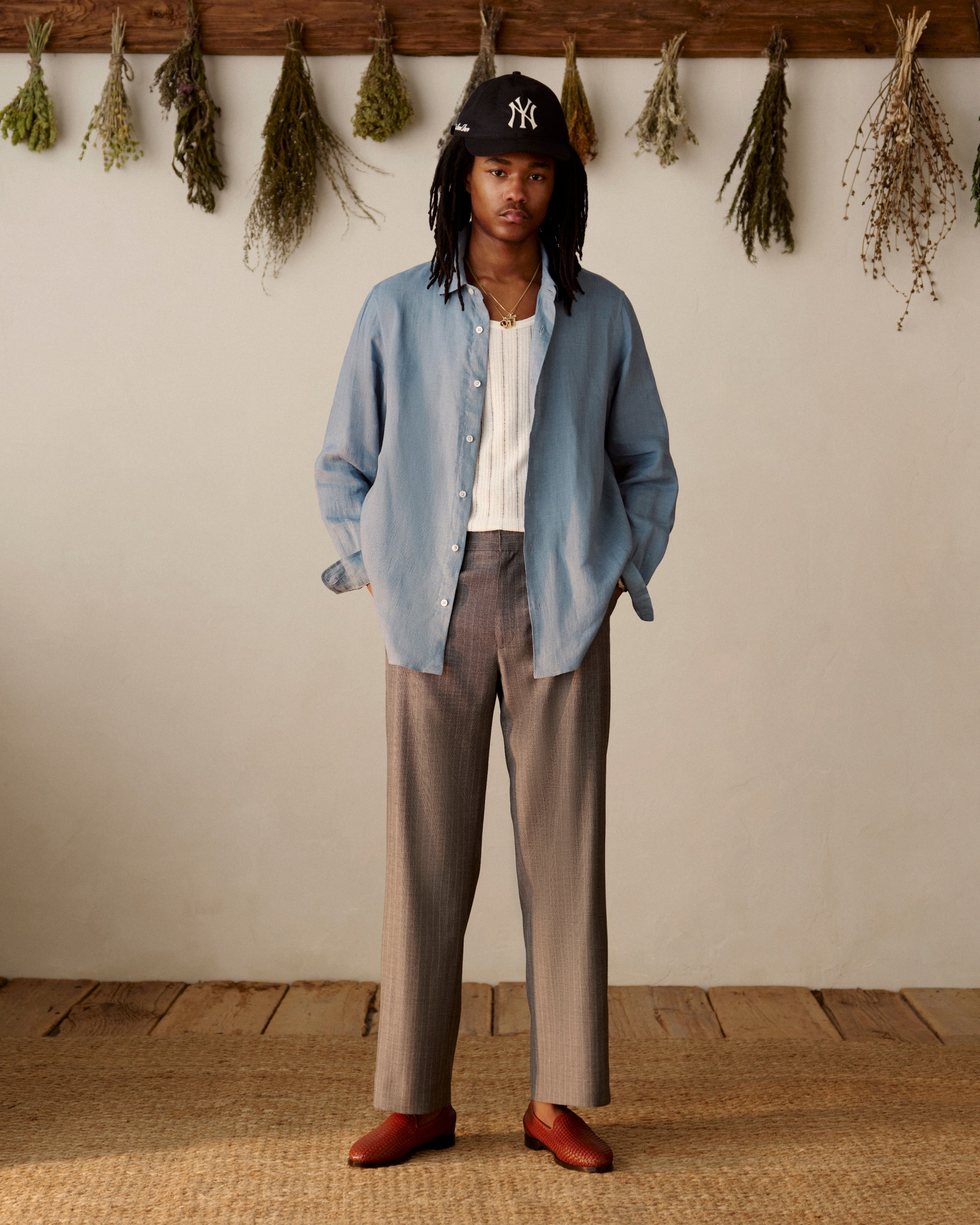 A person in a Long-Sleeve Linen Shirt stands indoors with dried herbs hanging behind them.