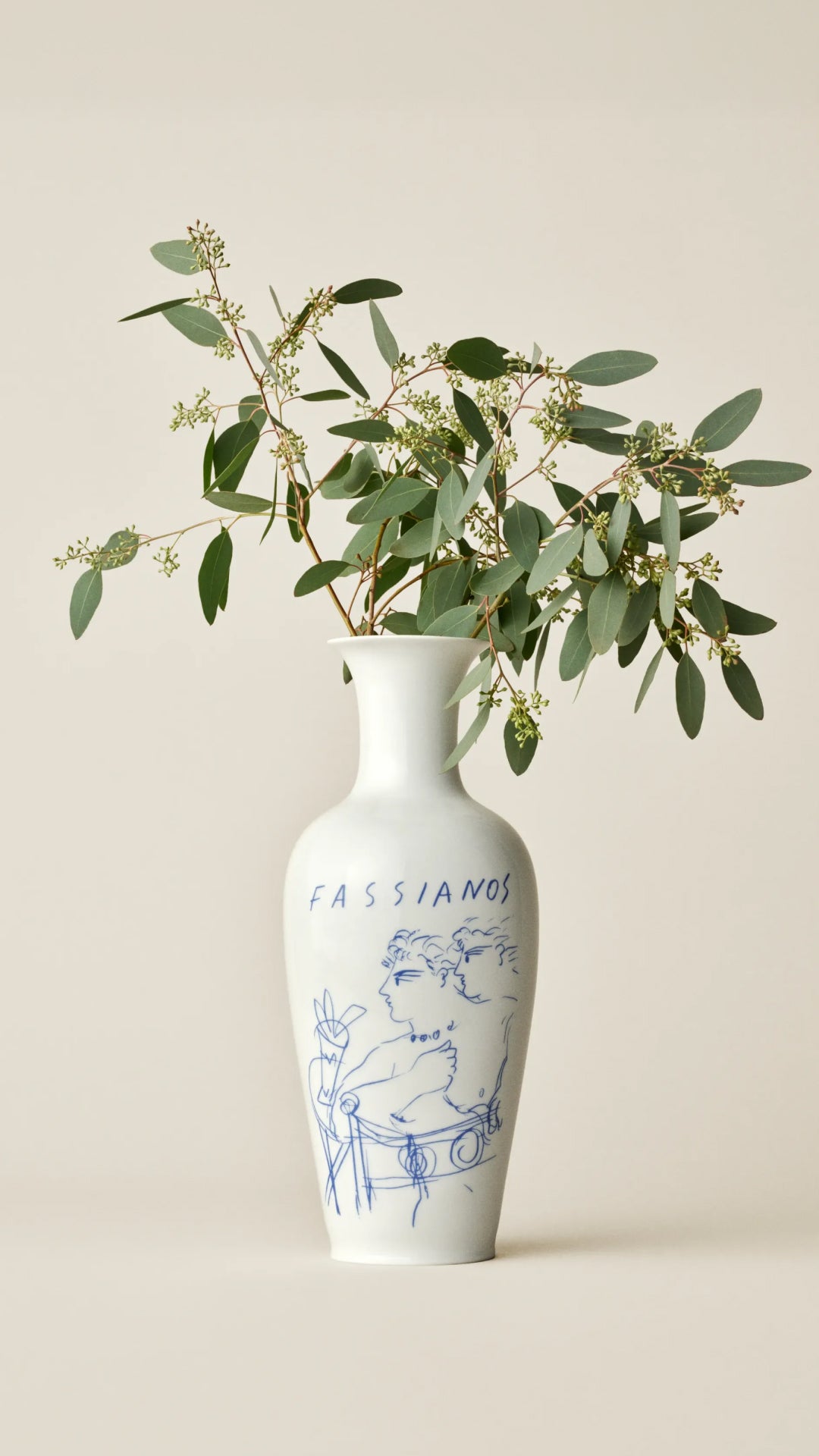 White vase with blue design and eucalyptus leaves on a beige background