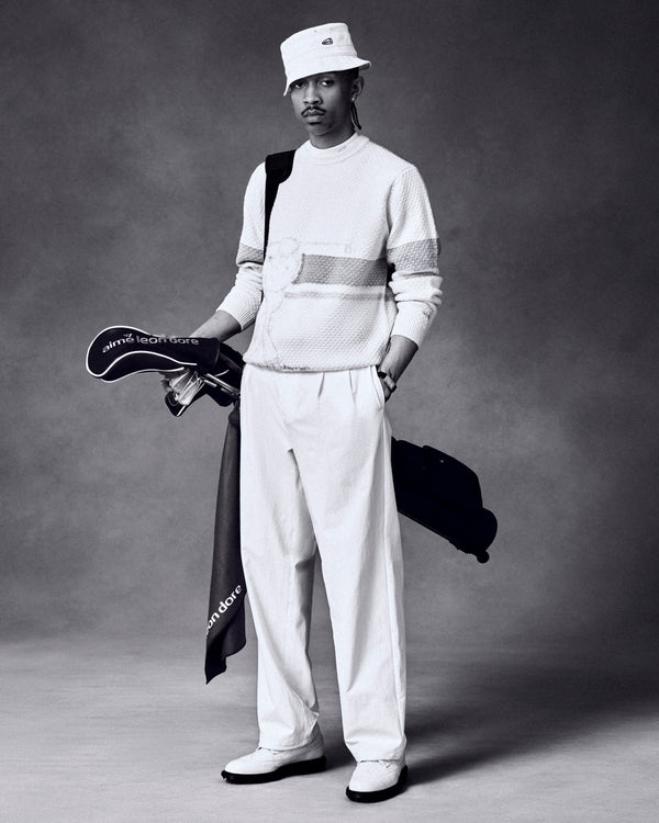A man in white with a bucket hat holds the ALD Golf Caddy Towel and clubs against a dark studio backdrop.