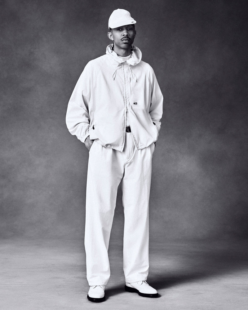 A man poses in the ALD Golf Lightweight Tips Windbreaker against a dark, textured studio background.
