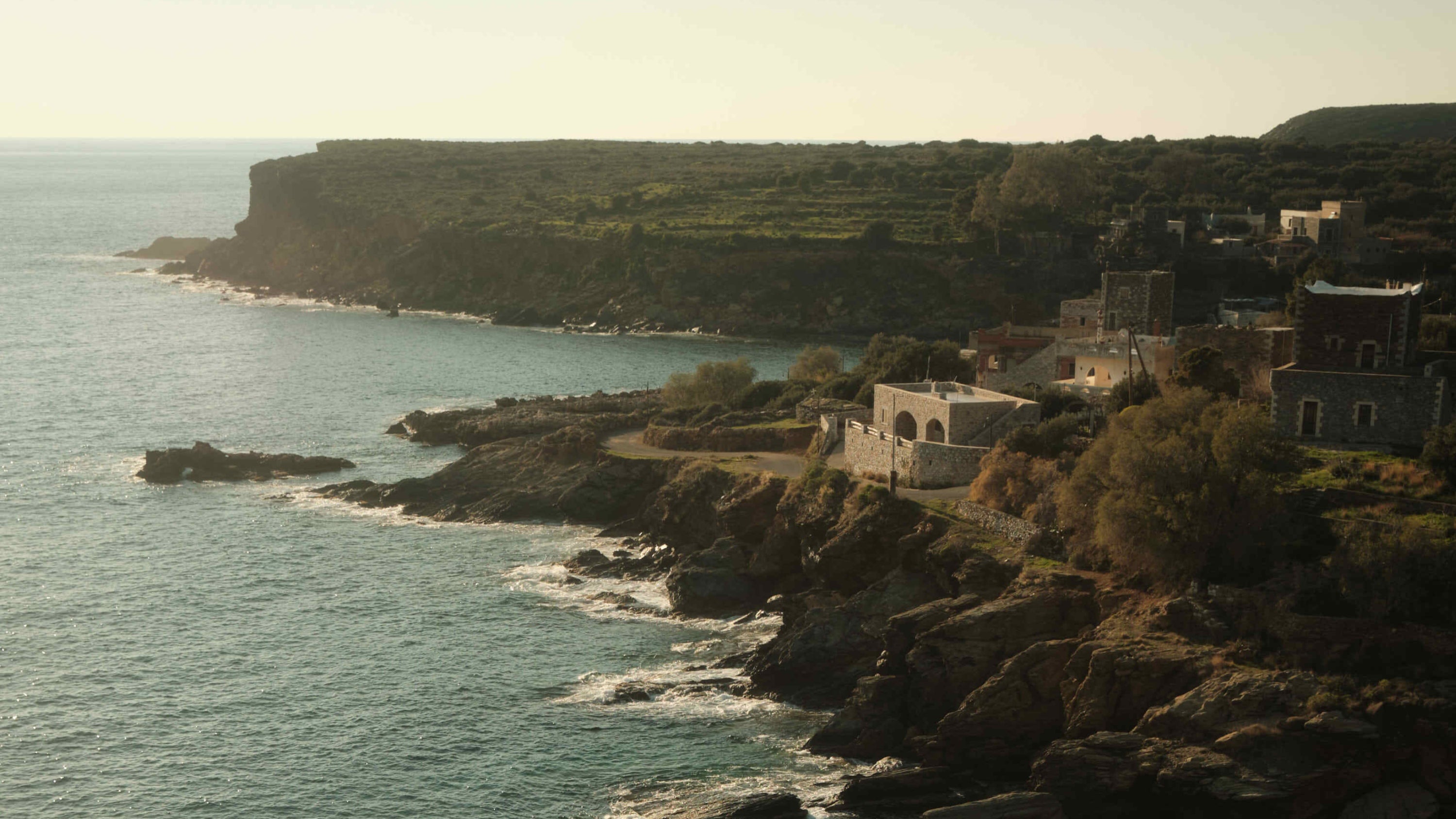 Coastal landscape with buildings on a cliff overlooking the ocean.