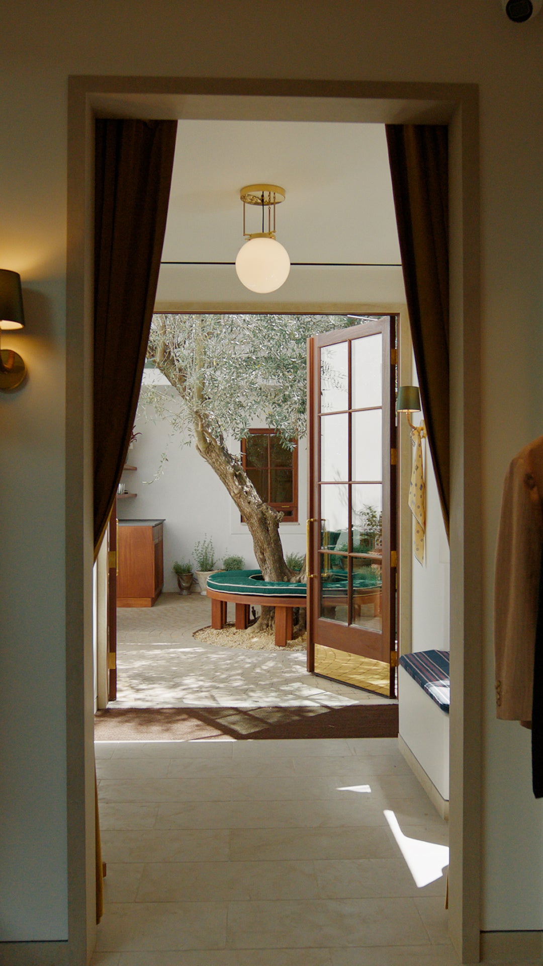 Open door leading to a patio with a tree and outdoor furniture