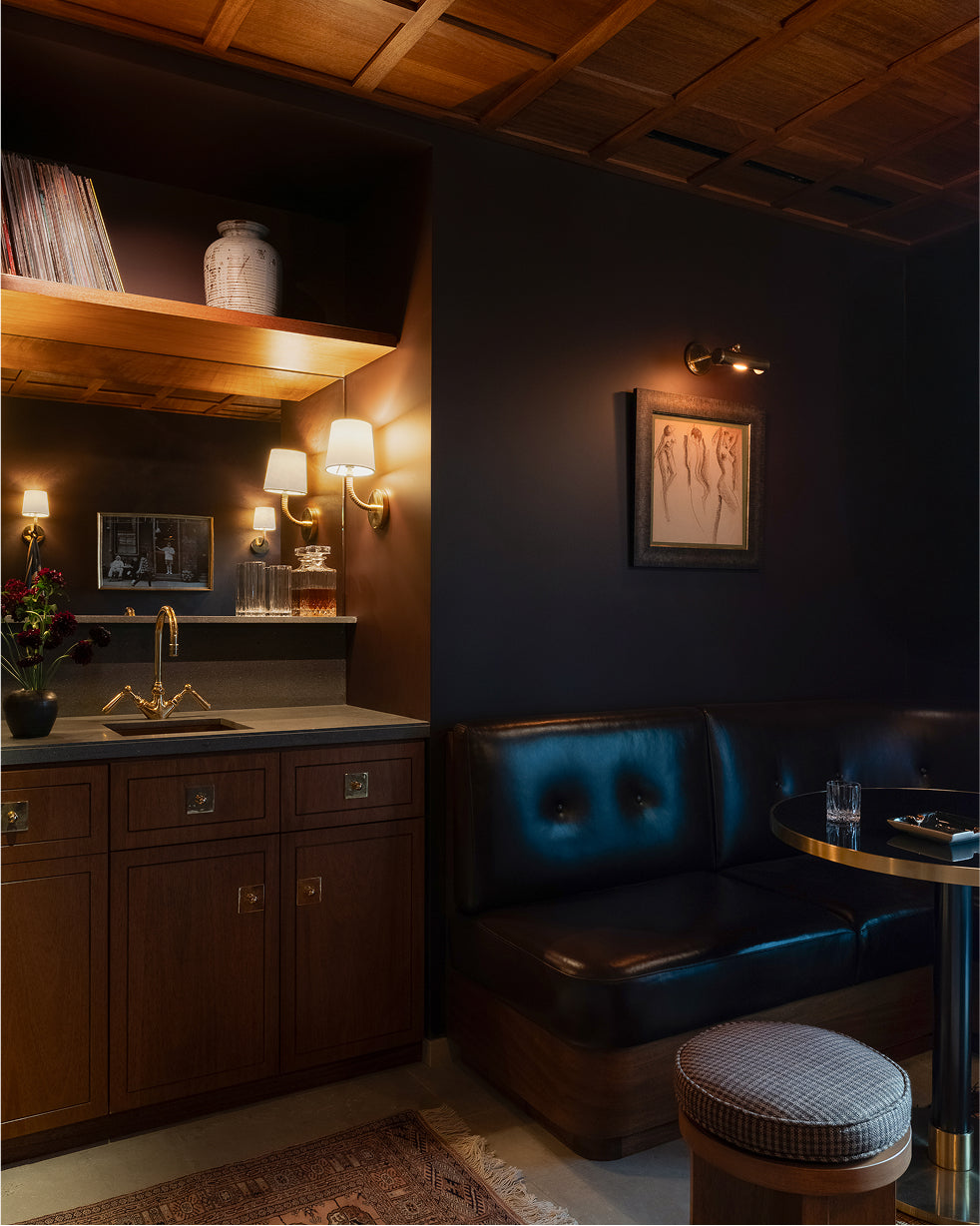 Dark interior of a bar with wooden shelves, blue booth, and dim lighting.
