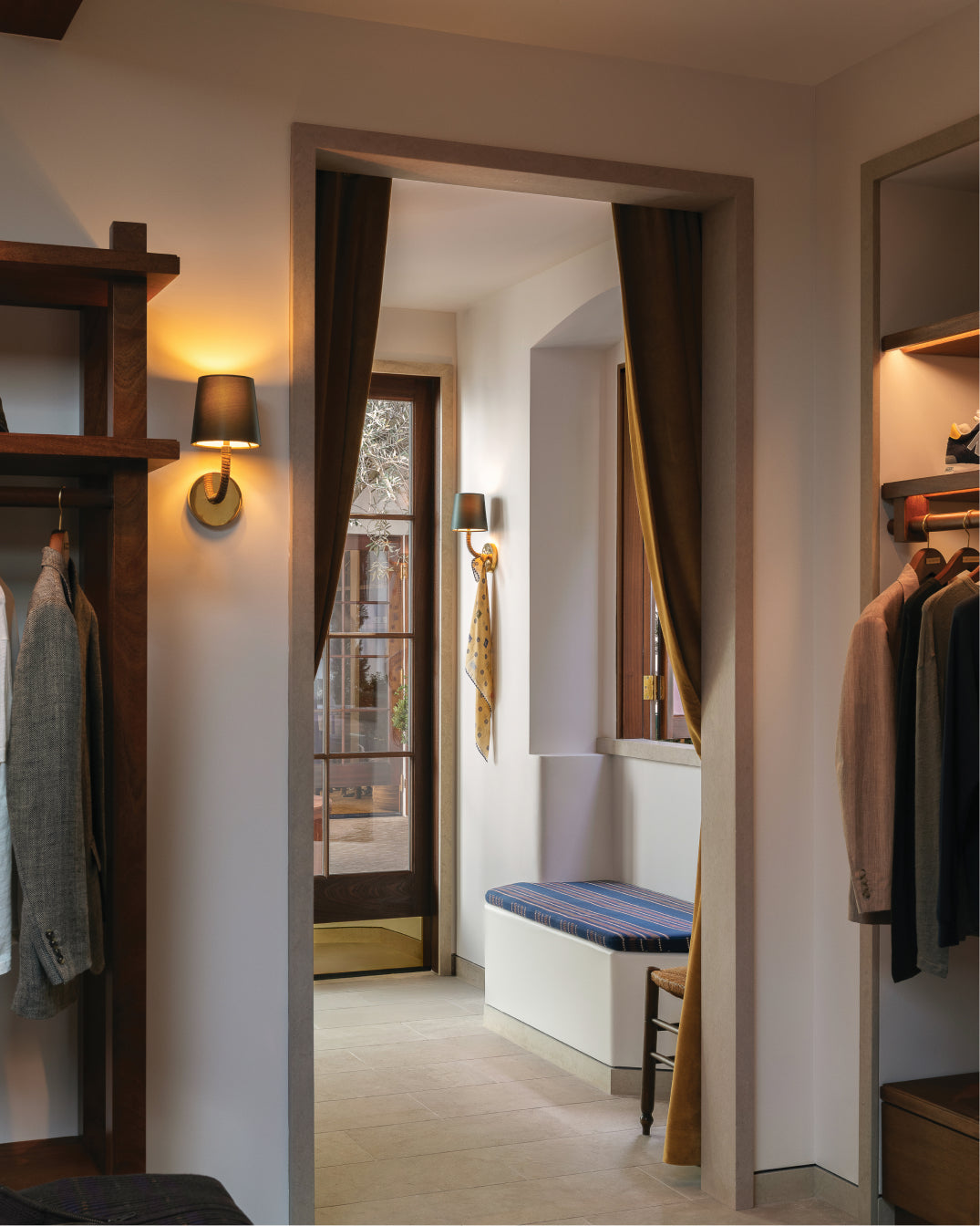 Closet interior with clothes and shelves, leading to a hallway.