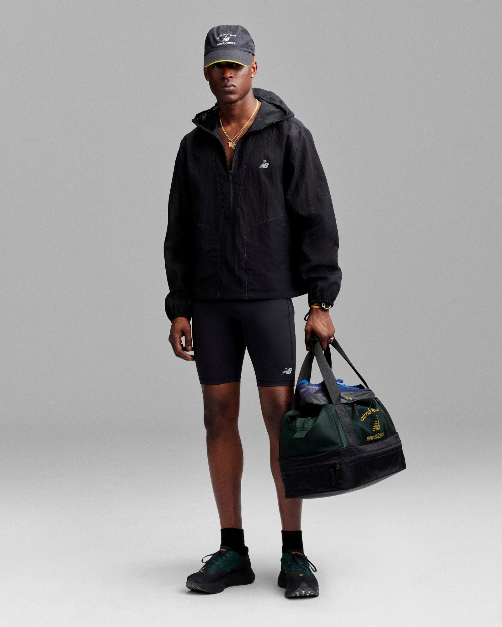 A person holds the ALD / New Balance Travel Duffle Bag against a gray background.