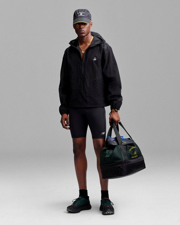 A person holds the ALD / New Balance Travel Duffle Bag against a gray background.